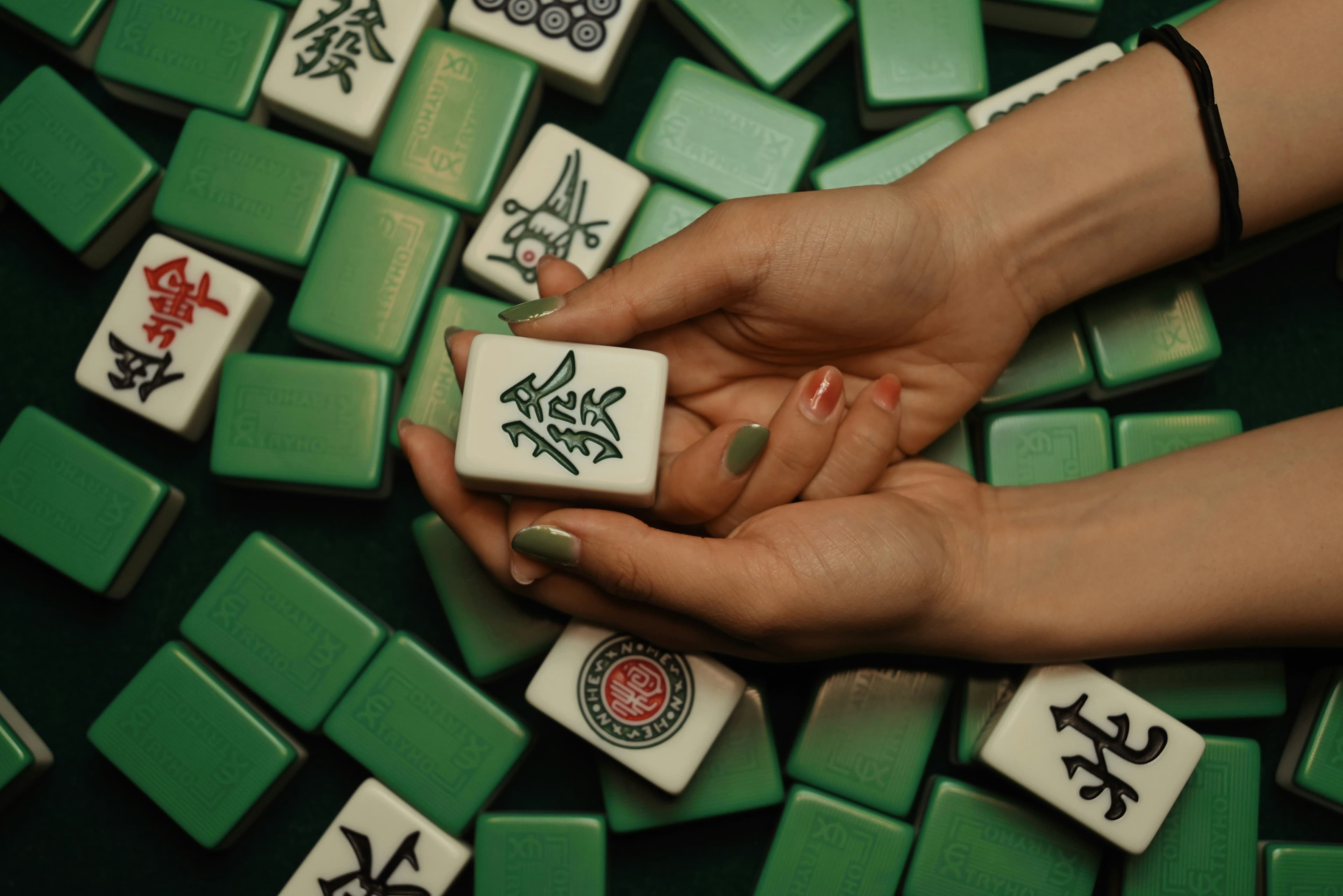 Hands holding mahjong tiles